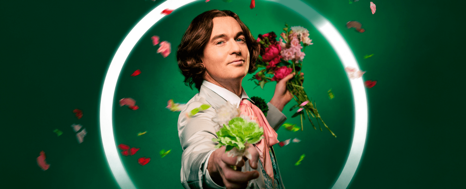A man against a green background with flowers floating around him