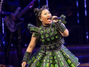 A woman wearing a green outfit singing into a microphone