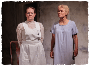 A woman in a white pinafore blue dress standing next to a woman in 