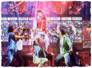 Man stood on table, everyone holding items pointing towards him