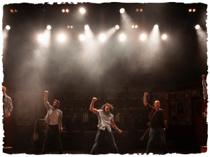 Men with fists in air, dimly lit stage