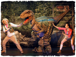 A man and a woman holding their hands out to ward off a raptor model