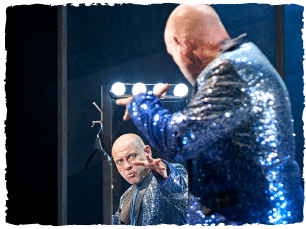 Man in sparkly blue blazer posing in mirror