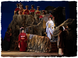 Performers lined up on a rock in red and white kaminos