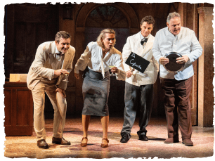 4 actors in a line on stage holding various props