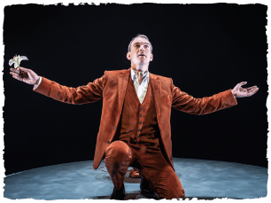 Man in orange suit down on one kneww; hands extended to side