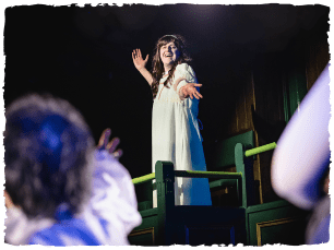 An actor stood on a balcony look down at another actor