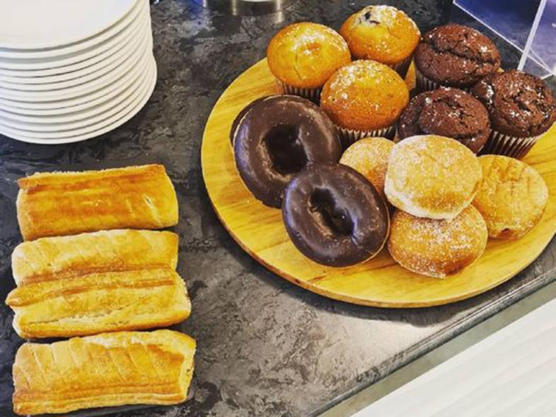 A selection of cakes, sausage rolls and pastries.