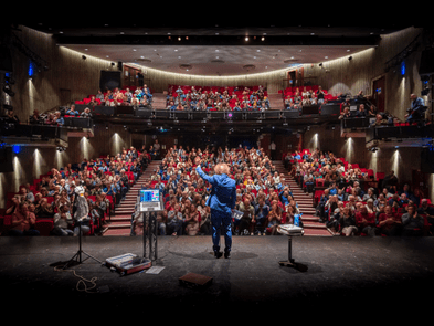 a comedian on stage facing an auditorium of people