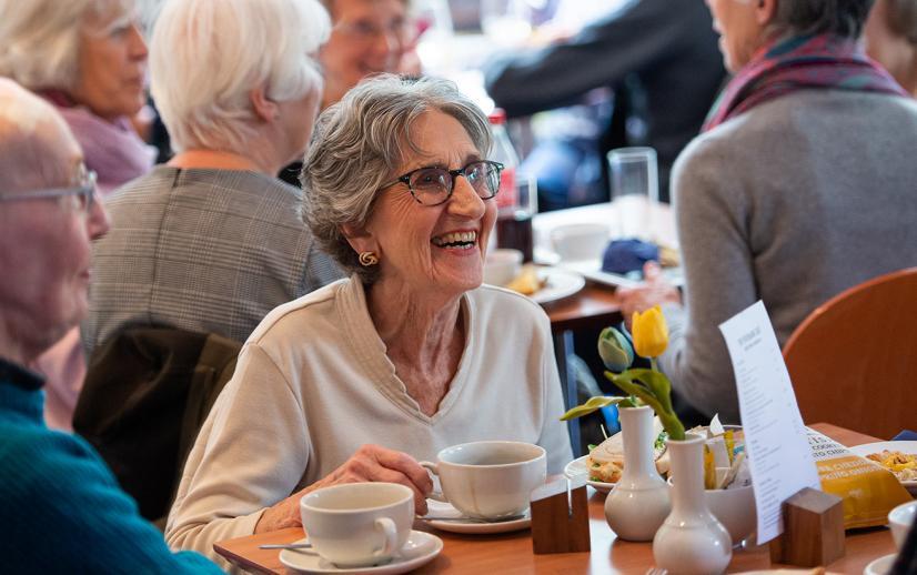 An image of a woman enjoying a coffee and laughing.