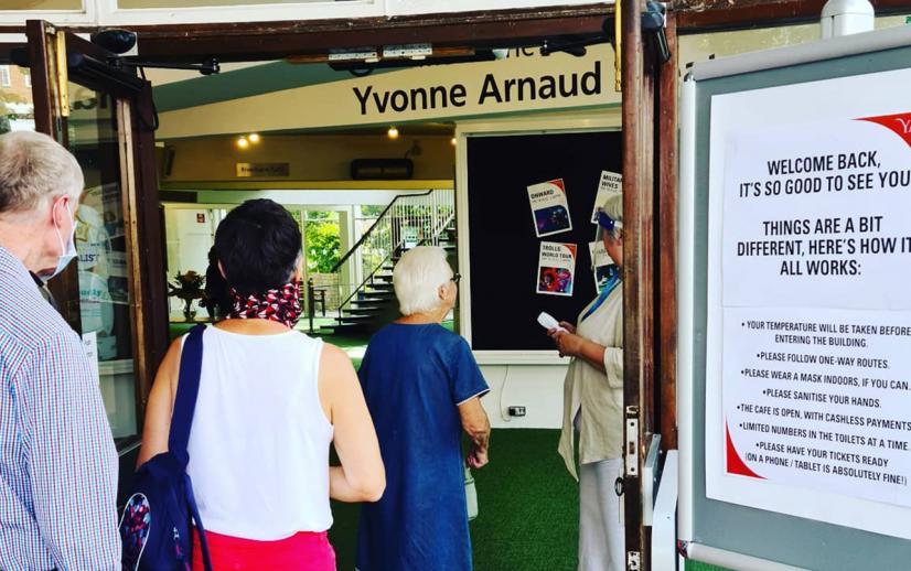 A member of staff welcomes customers back to the theatre in a Covid Secure way.