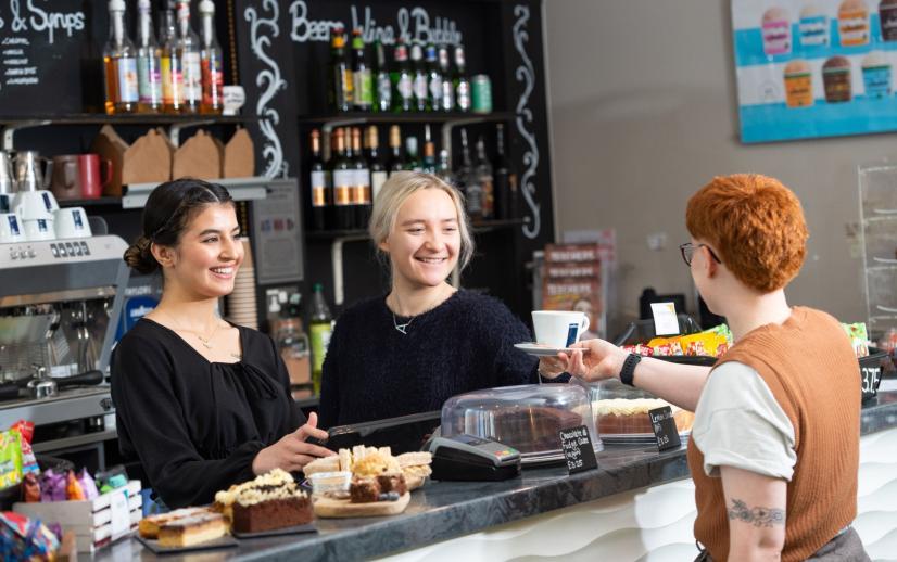 A customer being served at the bar by two smiling bar staff