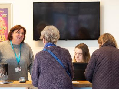 Image of our Box Office with two members of staff and two customers.