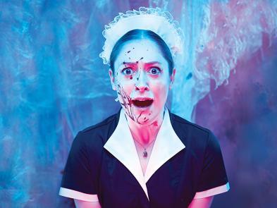 A woman dressed in a maid's outfit is screaming with blood on her face.