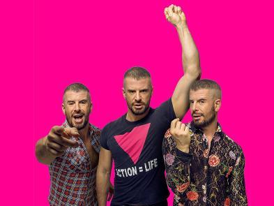 Three men stand in front of a hot pink background. One man has his arm raised making a fist.