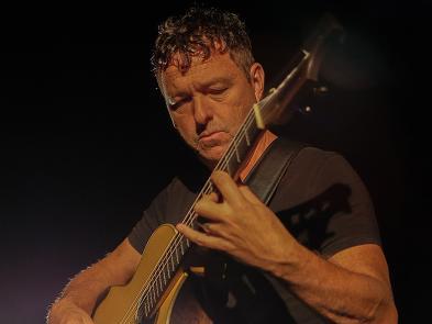 A man plays a guitar in a dark room