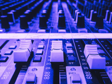 A sound desk showing several buttons and sliding dials.