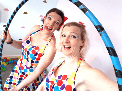 Two performers in colourful outfits holding a blue hoop