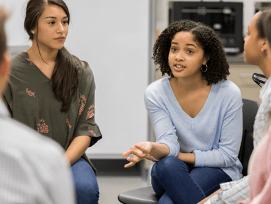 Teenagers talking in a circle in a white room