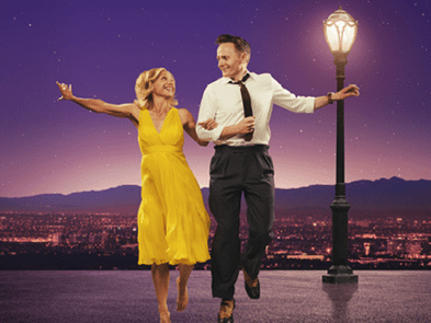 two dancers linking arms with the other arm outstretched in front of lamp post 