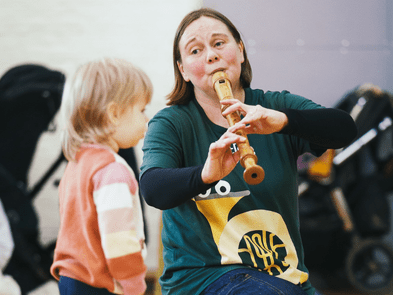 A performer playing the flute to a toddler