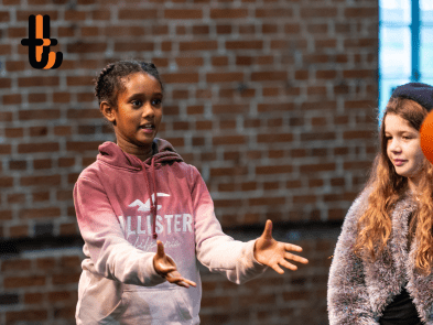 A girl with her arms open stood next to another girl 