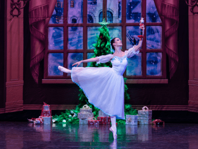 A ballet dancer en pointe dancing in front of a Christmas tree