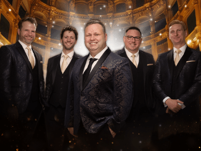 5 men in suits inside an opera house