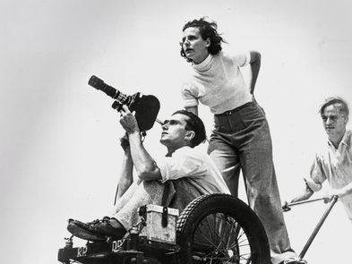 A camera operator with two people stood behind