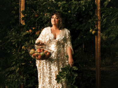 Kiri Pritchard McLean wearing a white dress holding a basket of fruit