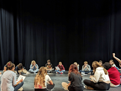Young people sat round in circle on floor in drama studio