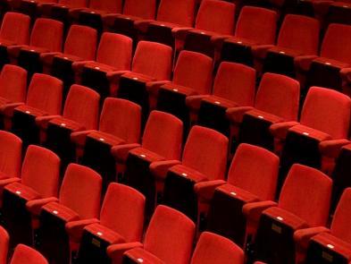 Rows of red cushioned theatre seating in the Yvonne Arnaud Theatre auditorium